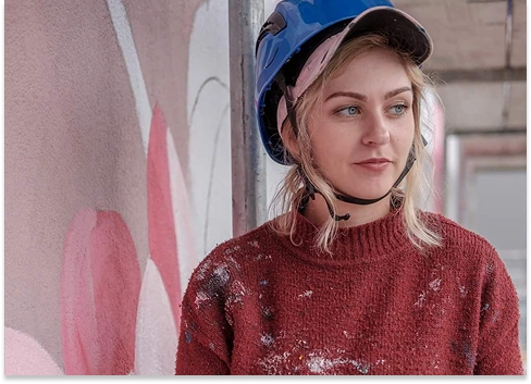 Kasia in blue helmet holding magazine near painted wall.