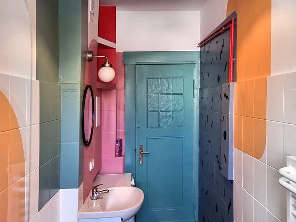 Colorful bathroom with pastel walls, sink, mirror, and turquoise door.